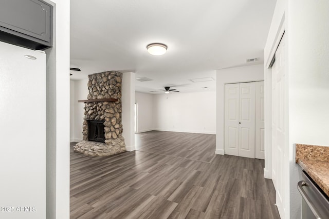 unfurnished living room with ceiling fan, dark wood-style flooring, visible vents, a fireplace, and baseboards