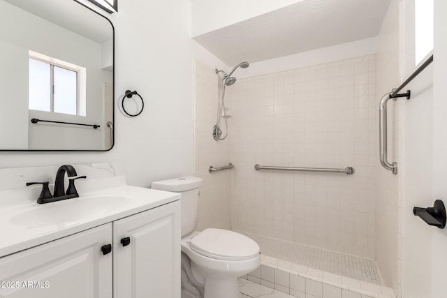 bathroom with vanity, toilet, and tiled shower