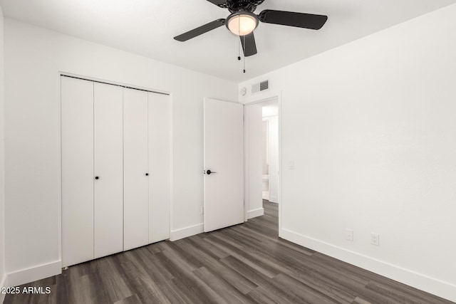 unfurnished bedroom with dark wood-style flooring, a ceiling fan, baseboards, visible vents, and a closet