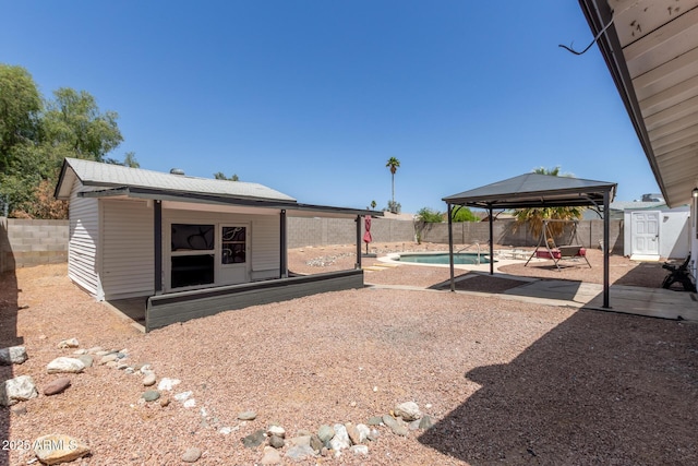 exterior space featuring a gazebo, a fenced backyard, a fenced in pool, a patio area, and an outdoor structure
