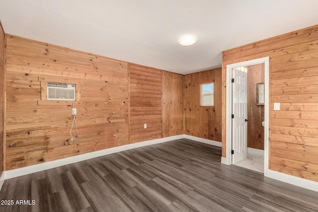 empty room with baseboards, wood walls, a wall unit AC, and dark wood-style floors