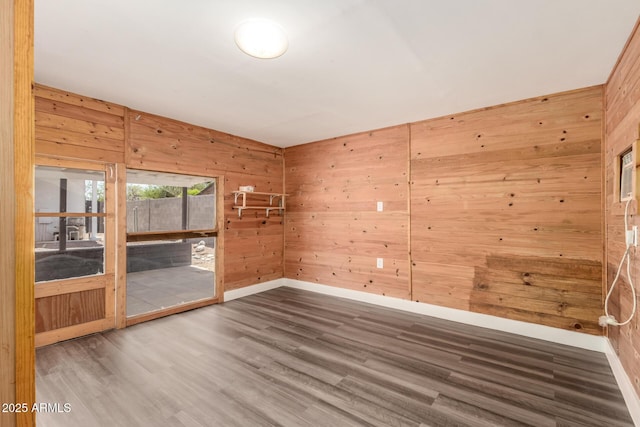 unfurnished room with wooden walls, baseboards, and wood finished floors