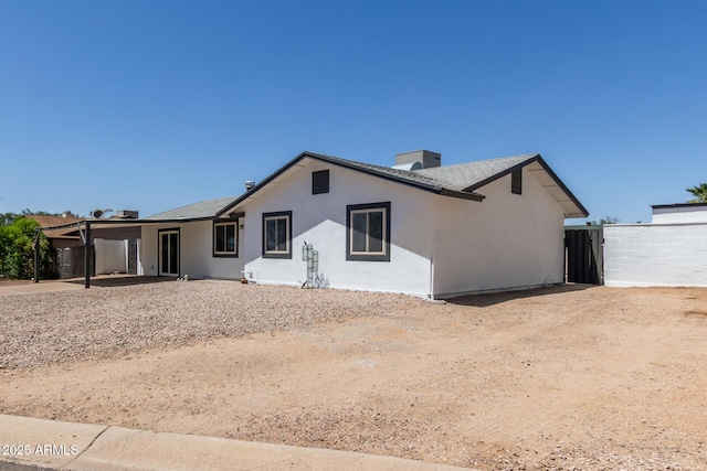 view of front of home with fence, stucco siding, and a chimney