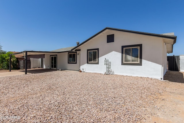 back of property with stucco siding and fence