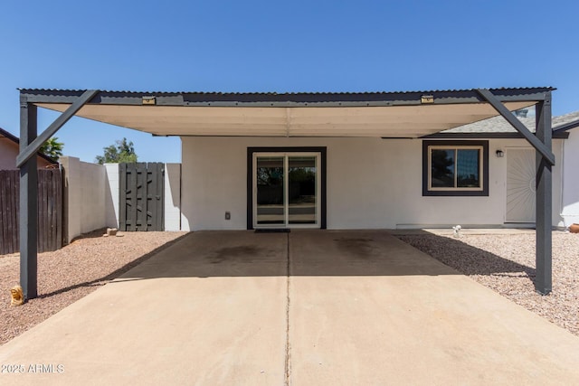 rear view of house featuring a patio, fence, and stucco siding