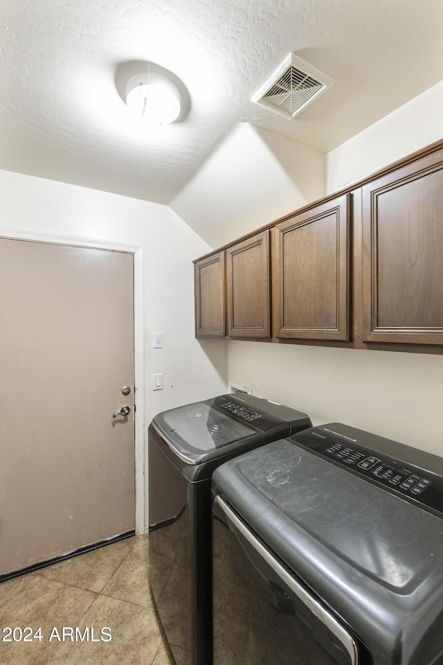 laundry room featuring cabinets, light tile patterned floors, and washer and clothes dryer