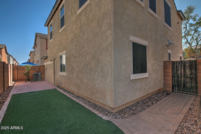 view of property exterior with cooling unit, a lawn, and a patio area