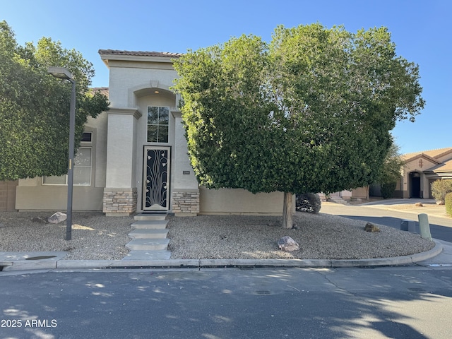 view of front of home featuring stucco siding, a tile roof, and stone siding