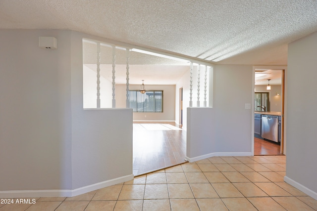 empty room with a textured ceiling and light hardwood / wood-style flooring