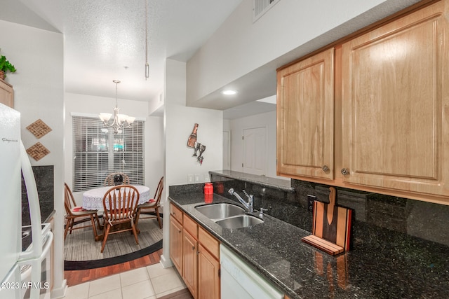 kitchen with a chandelier, decorative light fixtures, light hardwood / wood-style flooring, dark stone countertops, and sink