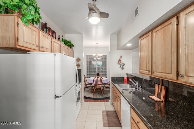 kitchen with pendant lighting, dark stone counters, ceiling fan with notable chandelier, white appliances, and sink