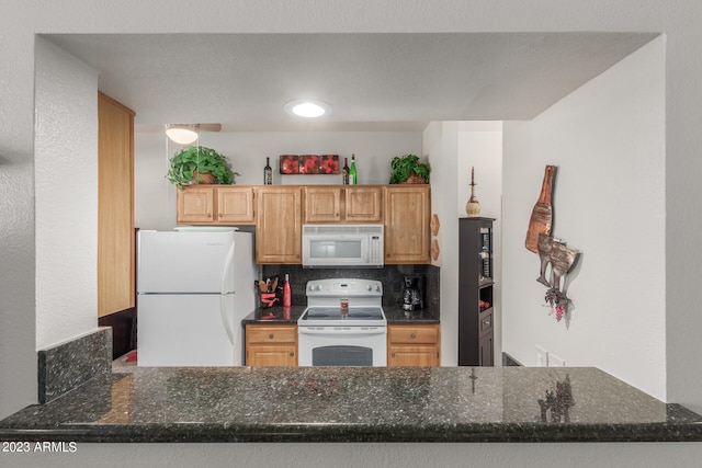 kitchen featuring white appliances, dark stone counters, and backsplash