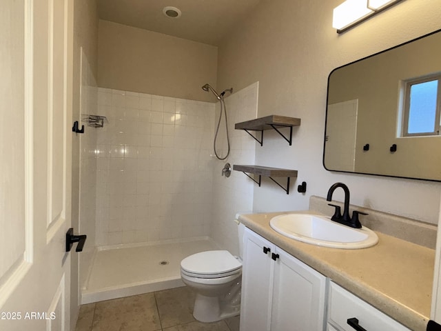 bathroom featuring toilet, tile patterned flooring, vanity, and a tile shower