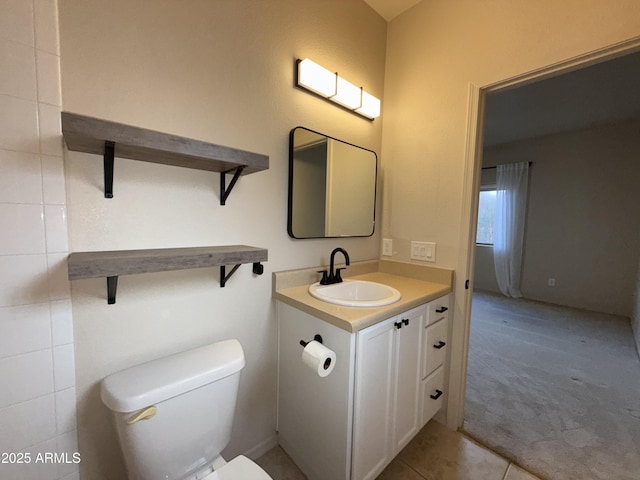 half bathroom featuring vanity, toilet, and tile patterned floors