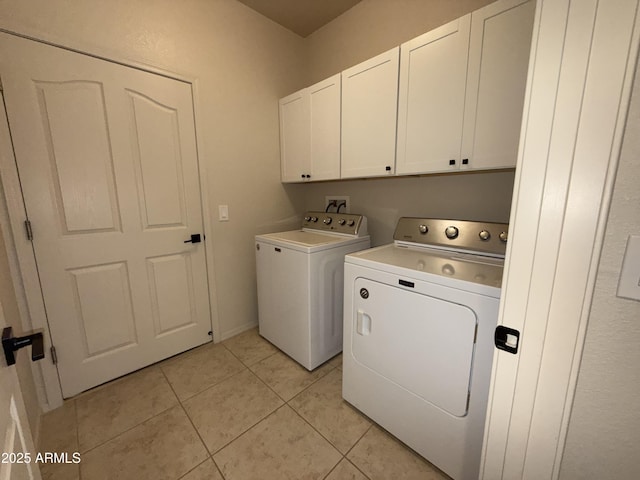 clothes washing area with light tile patterned floors, washing machine and clothes dryer, and cabinet space