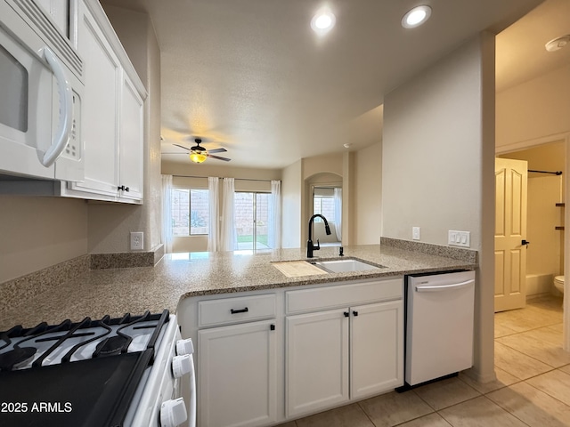 kitchen with recessed lighting, white cabinets, a sink, light tile patterned flooring, and white appliances