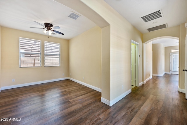 21017 W Edith Way, Buckeye, AZ 85396 - empty room with arched walkways, ceiling fan, dark wood-style floors, and healthy amount of natural light