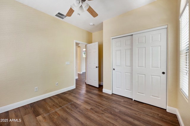 21017 W Edith Way, Buckeye, AZ 85396 - unfurnished bedroom with dark wood-style flooring, a closet, multiple windows, and a ceiling fan