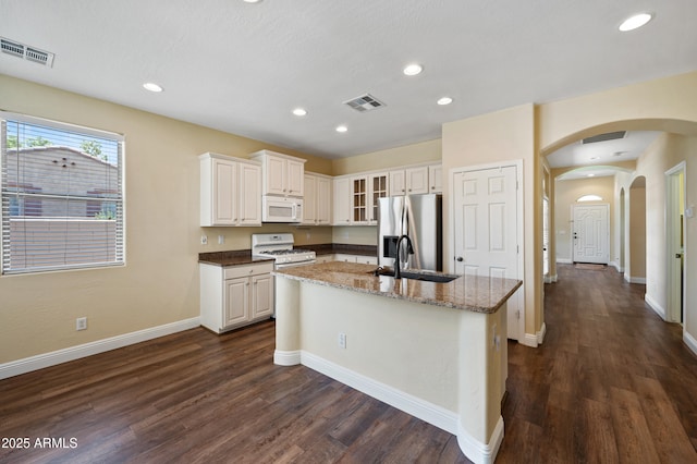 21017 W Edith Way, Buckeye, AZ 85396 - kitchen with white appliances, dark wood-style flooring, a kitchen island with sink, arched walkways, and recessed lighting