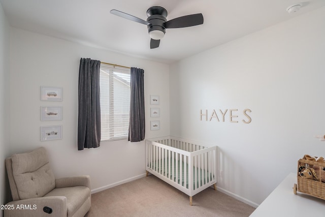 carpeted bedroom with a ceiling fan, a nursery area, and baseboards