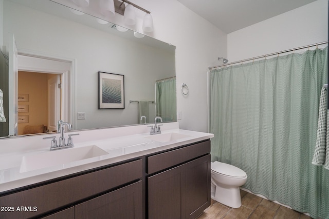 bathroom featuring double vanity, wood finished floors, a sink, and toilet