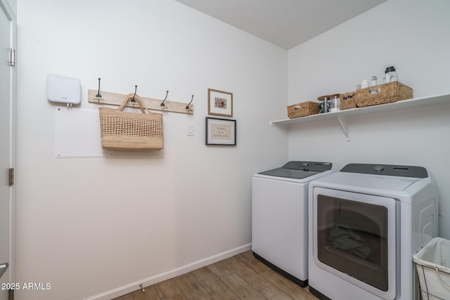 washroom with laundry area, wood finished floors, washing machine and clothes dryer, and baseboards