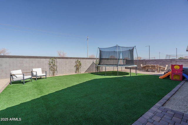 view of yard with a trampoline, a playground, and a fenced backyard