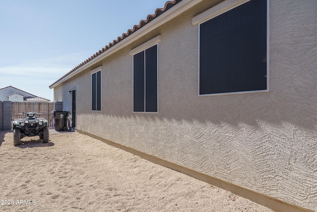 view of home's exterior with fence, a tiled roof, and stucco siding