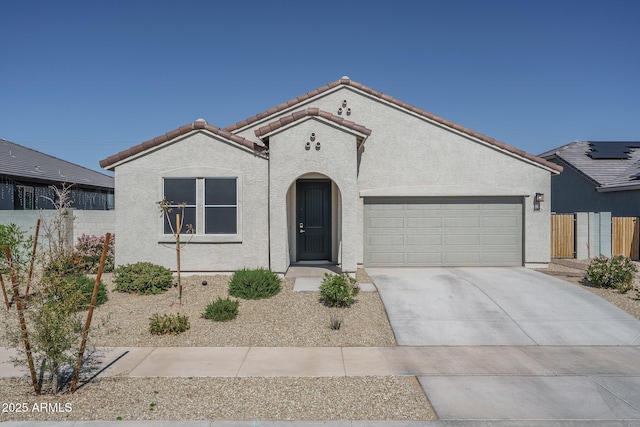 mediterranean / spanish-style house with concrete driveway, a tile roof, fence, and stucco siding