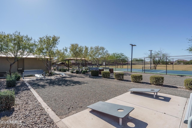 view of yard with a tennis court and fence