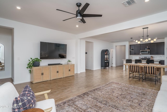 living area featuring ceiling fan with notable chandelier, light wood-type flooring, visible vents, and recessed lighting