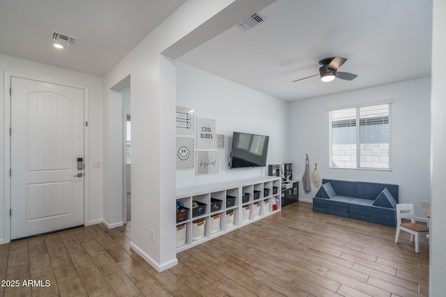 living area with visible vents, ceiling fan, and wood finished floors