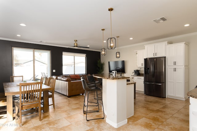 kitchen with a center island with sink, a breakfast bar, dark stone countertops, white cabinets, and stainless steel fridge with ice dispenser