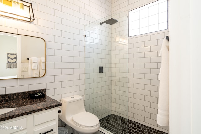 bathroom with toilet, vanity, tile walls, and a tile shower