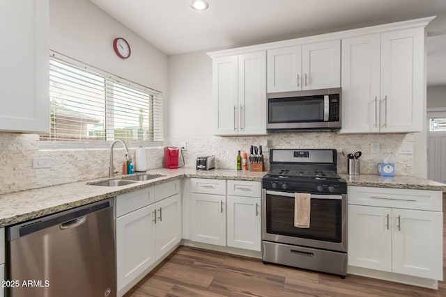 kitchen with appliances with stainless steel finishes, a sink, white cabinetry, and decorative backsplash