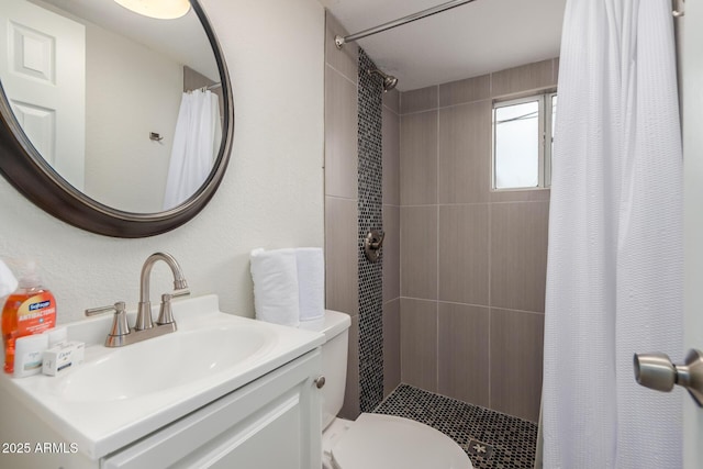 bathroom featuring tiled shower, vanity, and toilet