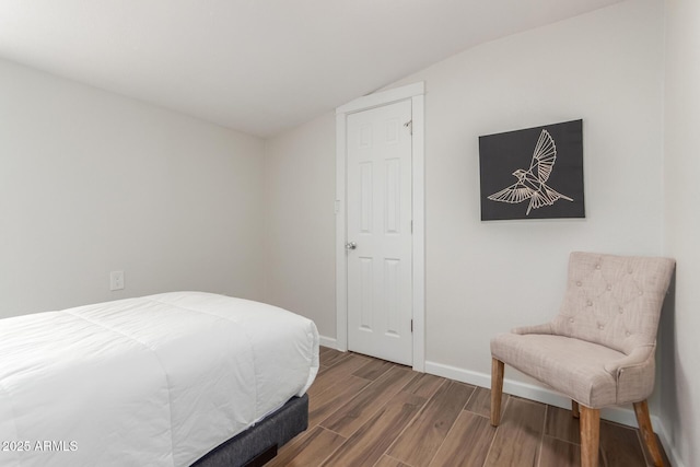 bedroom featuring vaulted ceiling, baseboards, and wood finished floors