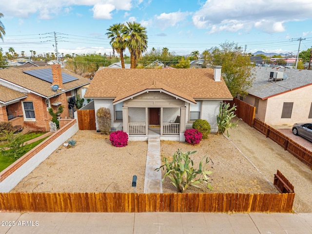 view of front facade with a shingled roof, fence private yard, a chimney, and a wall mounted AC