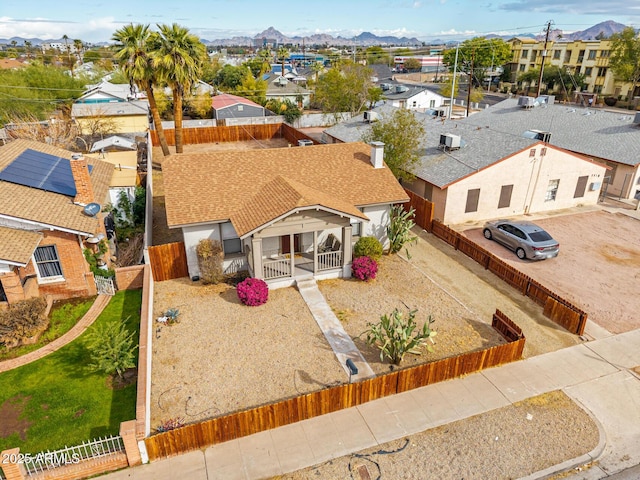 view of front of property featuring a shingled roof, a residential view, fence, and a mountain view