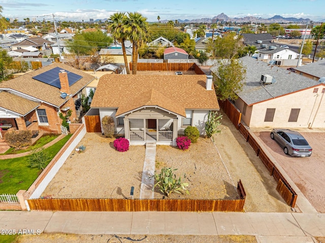 view of front of home featuring a residential view, roof with shingles, fence, and a mountain view