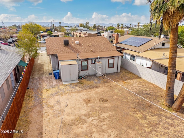 exterior space featuring a fenced backyard, a residential view, roof with shingles, an outdoor structure, and central air condition unit