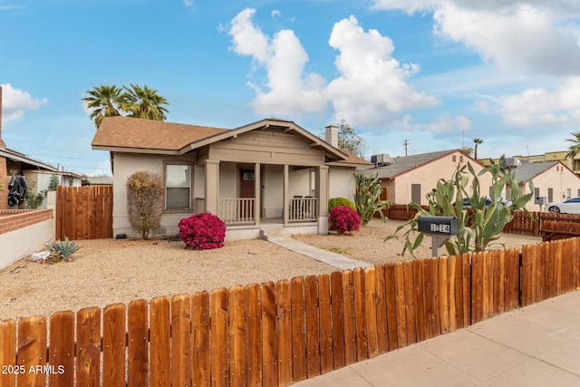 bungalow with covered porch, brick siding, and a fenced front yard