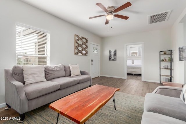 living area featuring ceiling fan, wood finished floors, visible vents, and baseboards