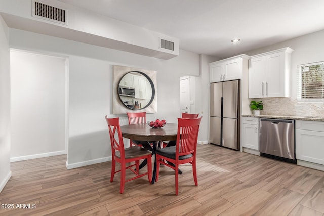 dining room with light wood-type flooring, baseboards, and visible vents