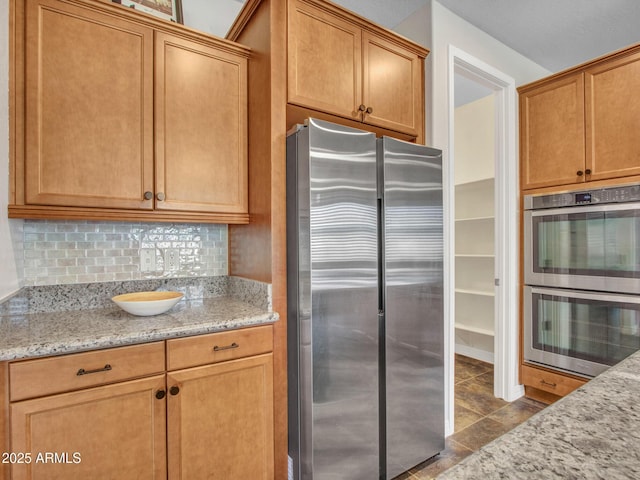 kitchen featuring light stone counters, appliances with stainless steel finishes, and backsplash