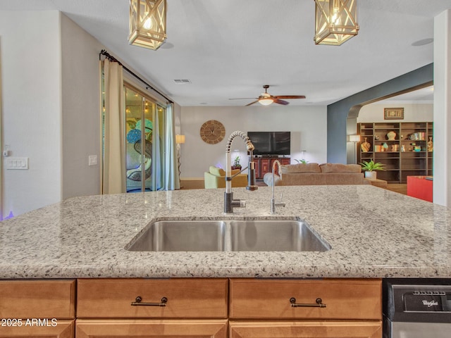 kitchen featuring ceiling fan, black dishwasher, sink, and light stone counters