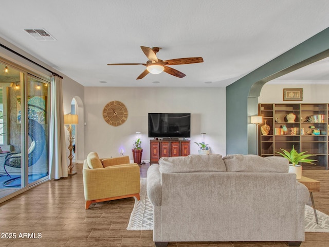 living room with hardwood / wood-style floors, crown molding, and ceiling fan