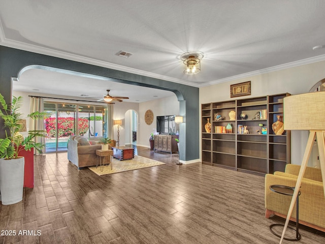 living room with ornamental molding, dark wood-type flooring, and ceiling fan