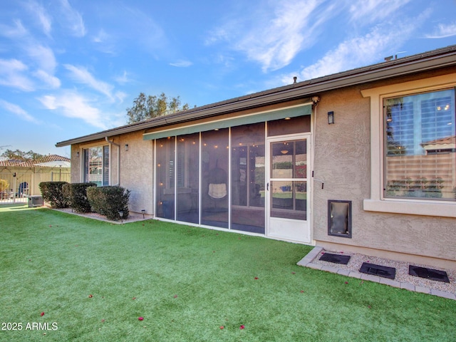 rear view of property with a lawn and a sunroom