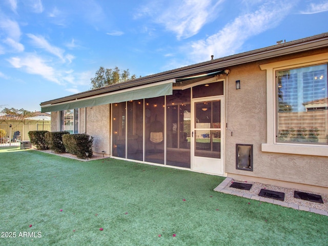 rear view of property featuring a sunroom and a lawn